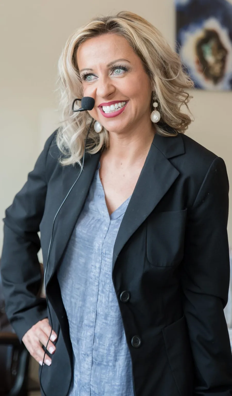 Krystalore Crews in a black blazer, smiling, wearing a speaker headset