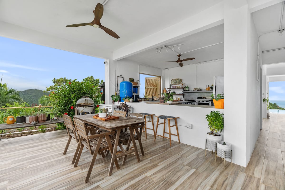 Open-air kitchen and dining area with ocean views and lush plants