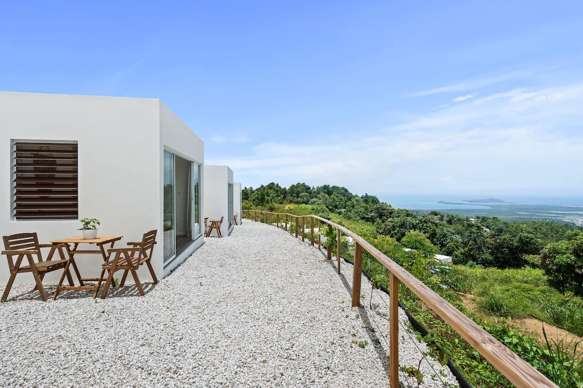 Hillside walkway with bistro seating overlooking tropical vegetation and coast
