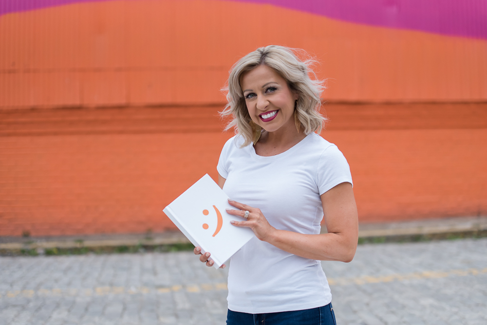 Krystalore Crews holding book with colorful mural background